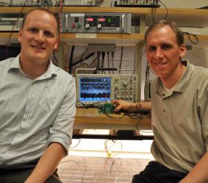 Assistant Professor Robert Pilawa and Christopher Barth at their PV research station. The solar panel below is attached to the buck converter in Barth's hand. At center, the screen shows the dithered ripple.