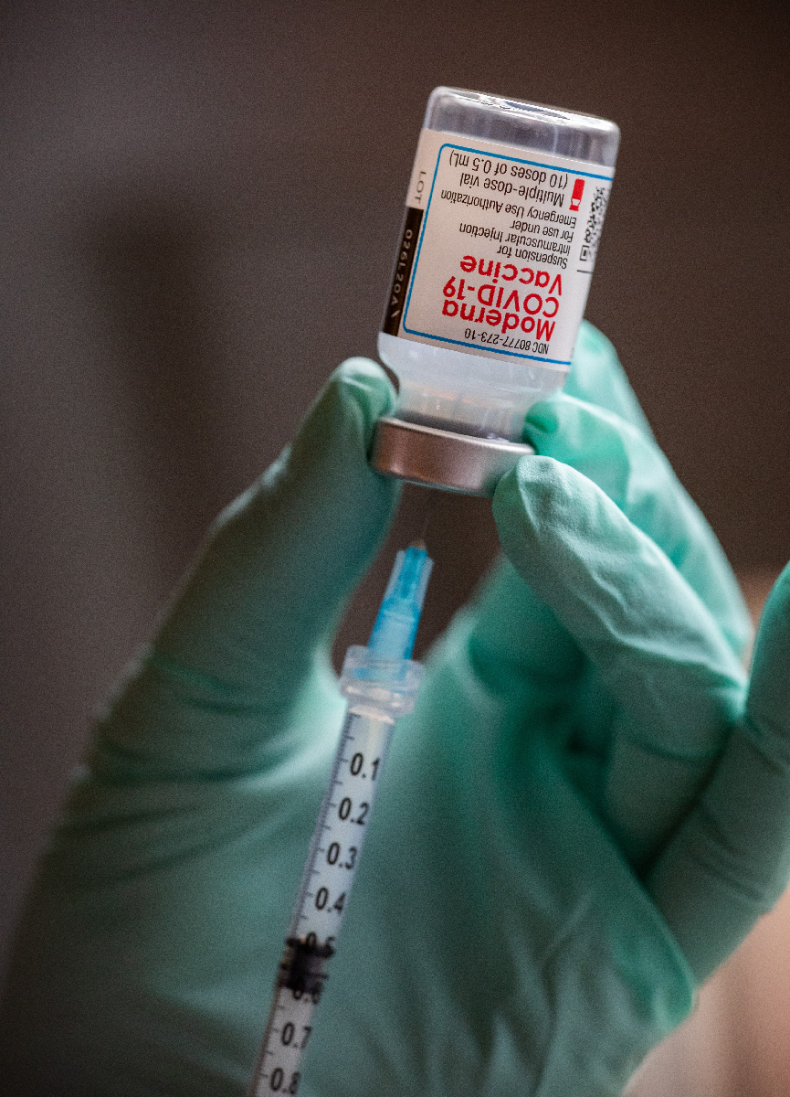 A medical professional draws a COVID-19 vaccine from a vial.